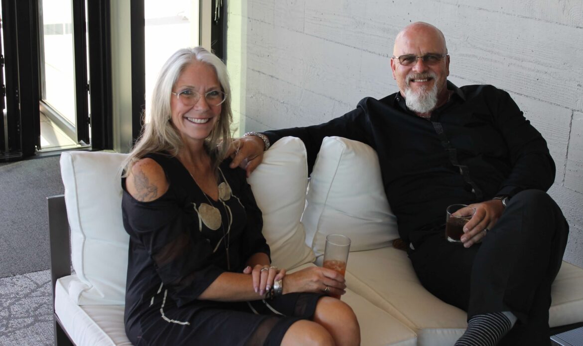 A image of two people smiling on a outdoor couch